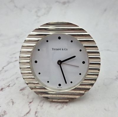 a silver clock sitting on top of a marble table