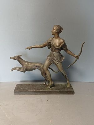 statue of a woman with a bow and a dog on a table