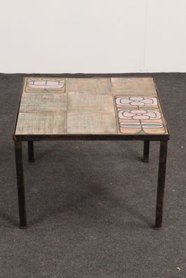 une petite table posée à même le sol, avec un plateau en carrelage
