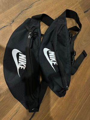 two black nike fanny bags on a wooden floor