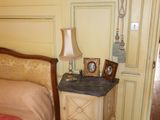 a bedroom with a bed and a table with a picture frame on it