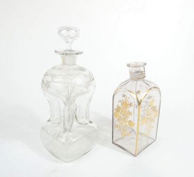 two clear glass bottles with gold designs on them sitting next to each other