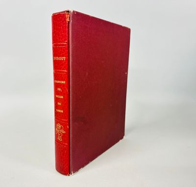 un vieux livre rouge posé sur une table blanche