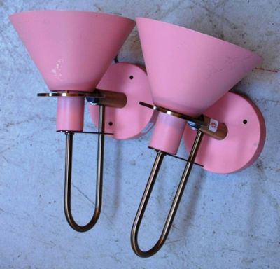 une paire d'appliques roses fixées à un mur en béton à l'aide d'un crochet métallique