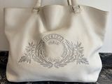 un sac fourre-tout en cuir blanc orné d'un blason sur le devant