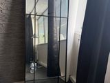 un grand miroir dans un coin de la pièce, près d'une fenêtre