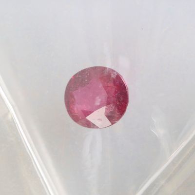 a close up of a red ruby stone in a clear bag