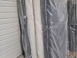 Plusieurs matelas sont emballés dans du plastique dans un local de stockage