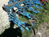 une charrue bleue qui est posée dans l'herbe