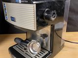 the coffee machine is sitting on a wooden table next to a cup of coffee