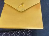a close up of a yellow purse and tie on a blue surface