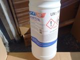 une main tenant une bouteille remplie de liquide devant une boîte en carton