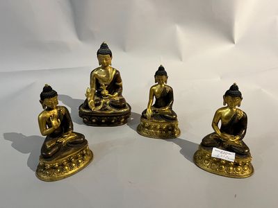 trois statues de Bouddha en or sont assises sur une surface blanche