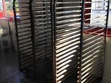 several trays of food sit on a metal rack in front of a window