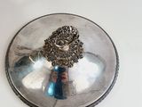 a silver plate with a face on it on a table