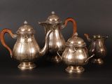four pieces of silver tea and coffee set on a black background