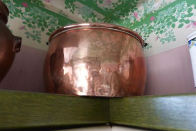 a copper pot sitting on top of a wooden shelf