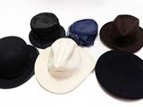 Plusieurs chapeaux sont disposés en cercle sur une surface blanche