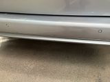 the rear end of a silver car with a sticker on it ' s bumper