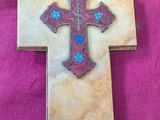 une croix ornée d'une fleur bleue et un bol posé par terre