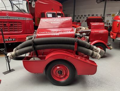 un camion de pompiers rouge muni d'une lance à eau à l'arrière