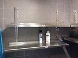 a metal shelf in the middle of a tiled bathroom