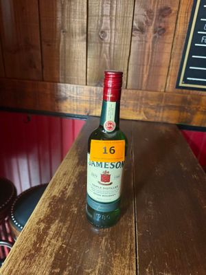une bouteille de Jameson posée sur une table en bois dans un bar