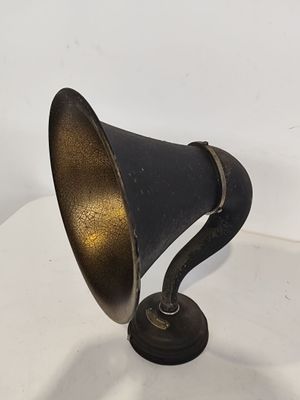 une lampe ancienne noire et dorée posée sur une table blanche