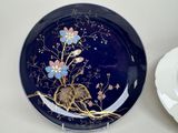 a blue plate with gold and pink flowers on it next to a white plate