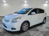 Une Toyota Sienna blanche est garée dans une pièce au sol carrelé.