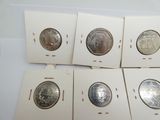Six types différents de pièces d'argent sont exposés dans une boîte blanche.