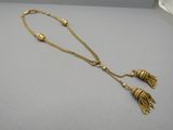 a gold necklace with tassels and beads on a gray surface