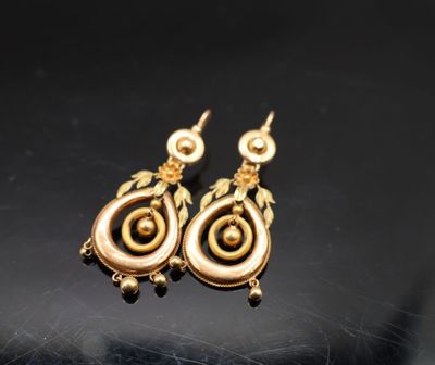 un gros plan sur une paire de boucles d'oreilles en or posées sur une surface noire