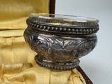 a silver bowl sitting in a case on a yellow cloth