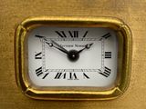 a gold clock with roman numerals on the face