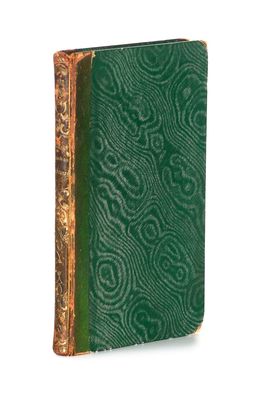 un vieux livre à la couverture verte posé sur une surface blanche
