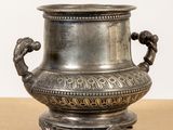 a silver vase sitting on top of a wooden table
