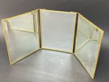 three glass panels with gold trims on a gray surface