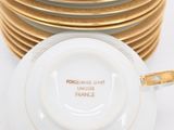 a stack of plates with gold rims on a white table