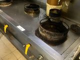 une cuisinière sale dans une cuisine professionnelle, avec des casseroles et des poêles posées dessus