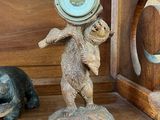 une étagère en bois sur laquelle se trouvent une horloge et une statuette d'ours