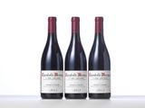 three bottles of red wine sitting on top of a table