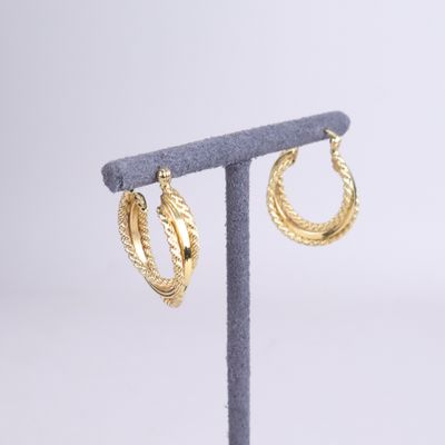 a close up of a pair of gold hoop earrings on a stand