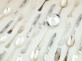 many spoons and forks laid out on the table