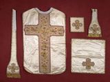 an image of a priest ' s vest, cross, and other religious items on a red background