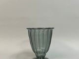 une photo d'un vase en verre vert posé sur une table blanche