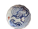 assiette bleue et blanche ornée d'un dragon, posée sur un socle