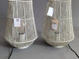 pair of white lamps with tags attached to them sitting on a table