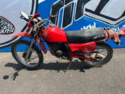 une moto rouge garée devant un mur bleu et blanc