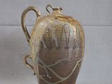 a brown vase with a bird on it on a table